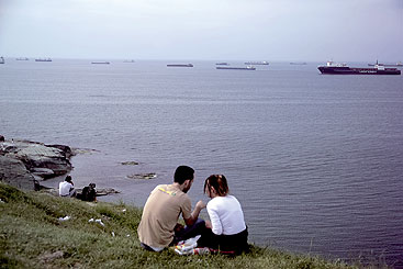 Credit: DRP/Mello a group of people sitting next to a body of water