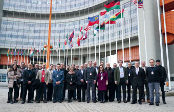 a group of people standing in front of flags and the UN building in Vienna