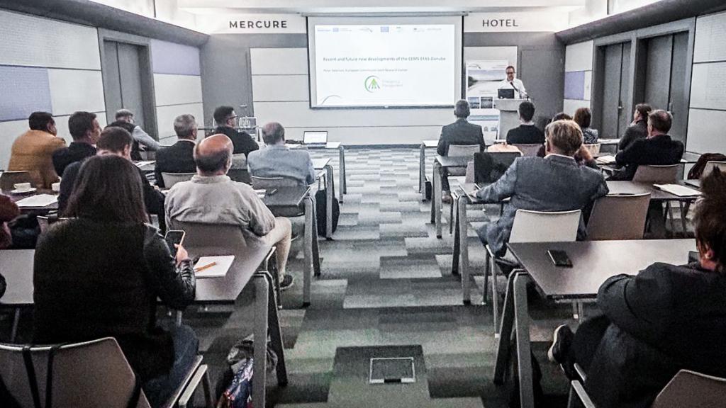 Group of people sitting in a room in front of a large presenting screen 