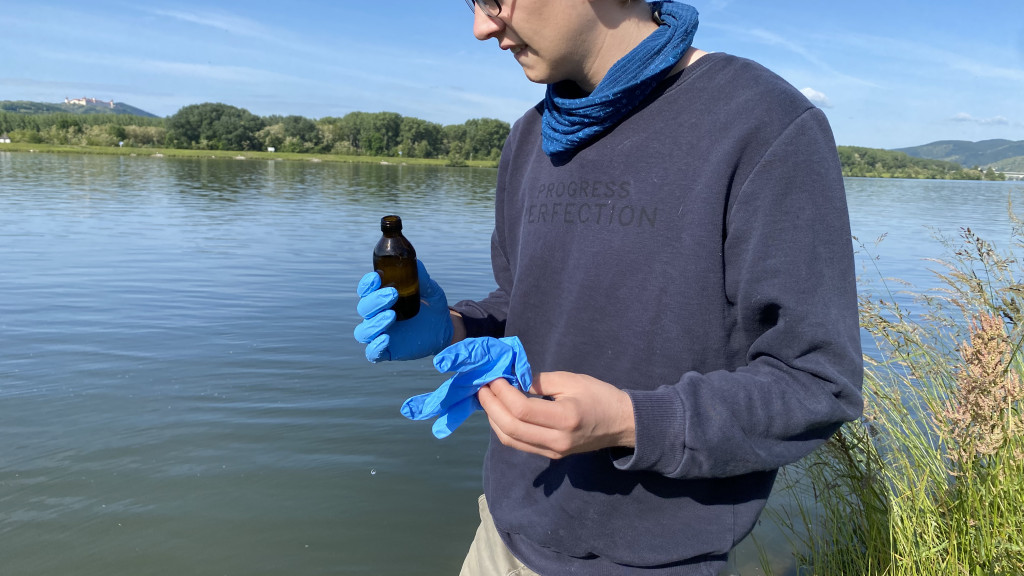 ICPDR a man stands at the river with a vial in his hand