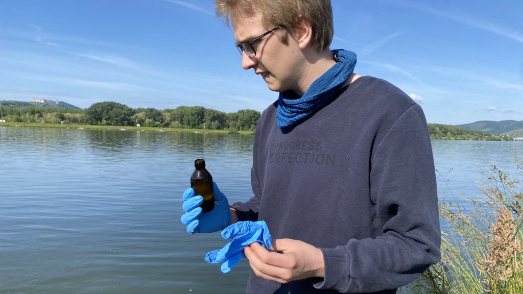 a man stands at the river with a vial in his hand 