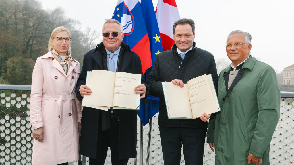 Two men hold a book in their hands and are sandwiched between a man and a woman