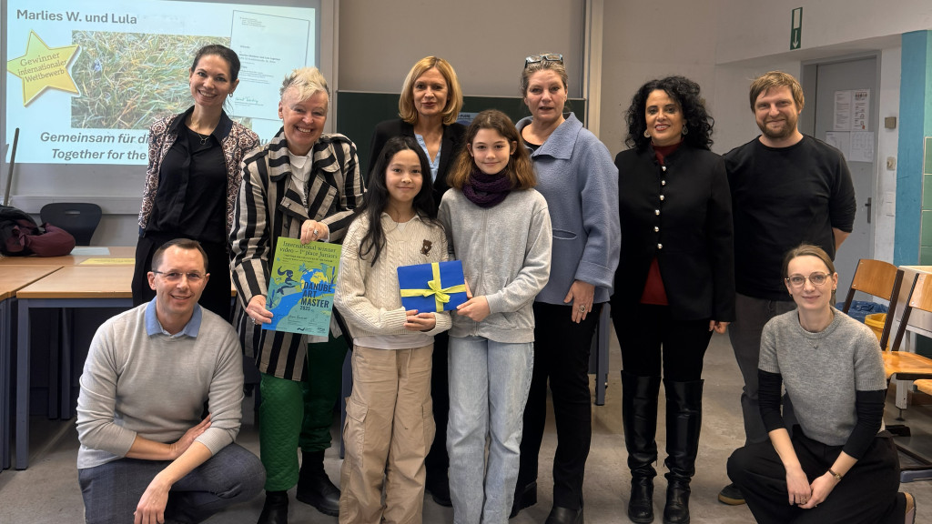 Two young female students holding an award in a classroom. 