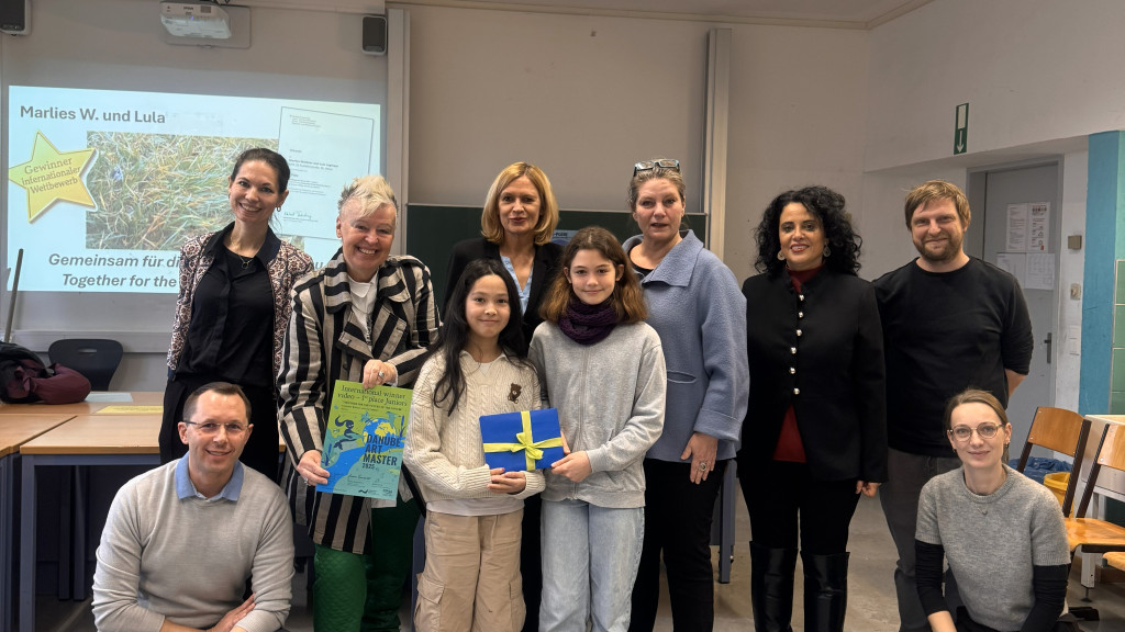 Two young female students holding an award in a classroom. 