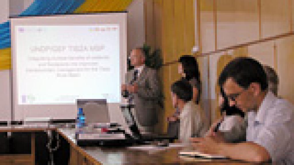 A presenter and a group of people sitting in a meeting room