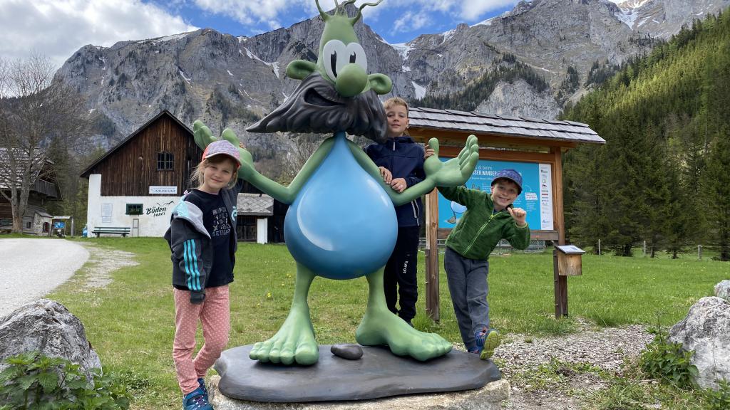 Children posing with Cartoon statue in front of a mountain landscape  
