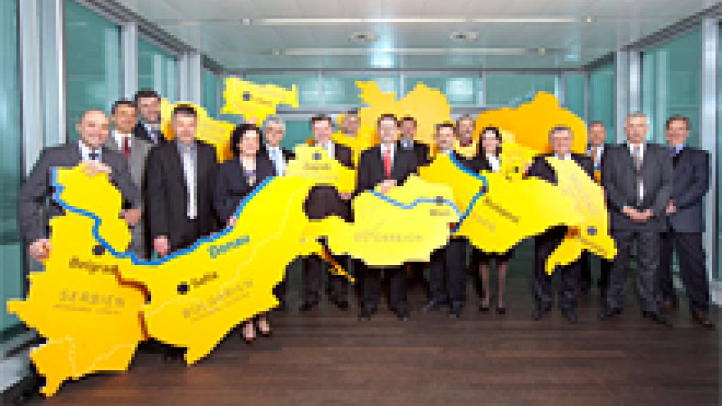 A group of people holding up country shapes posing for a picture 