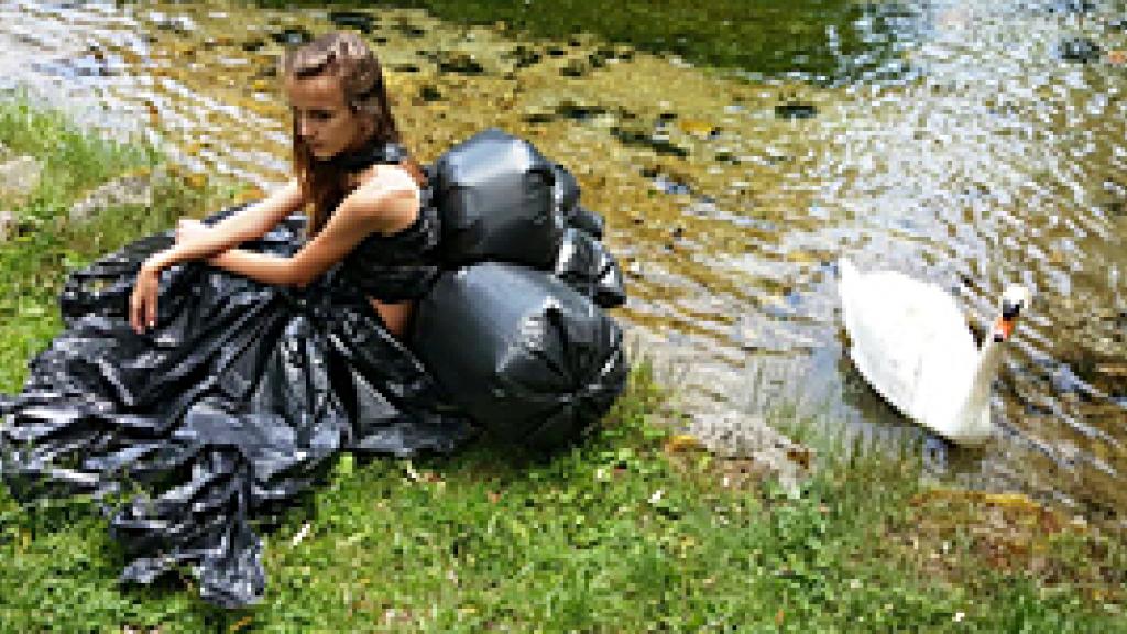 Woman sitting next to a swan in a river