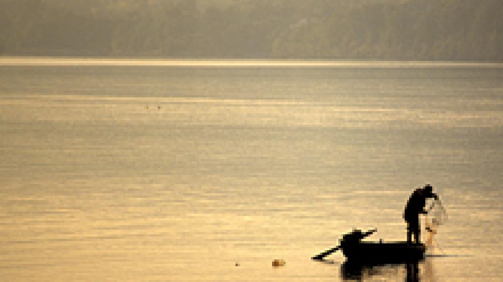 a fisherman standing on a boat on a body of water