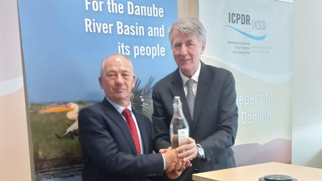 Two ambassador pose holding a glass bottle with water
