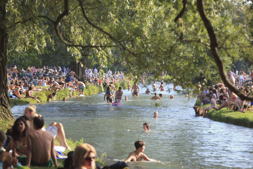 crowds of people on the banks of a river, some in the water  