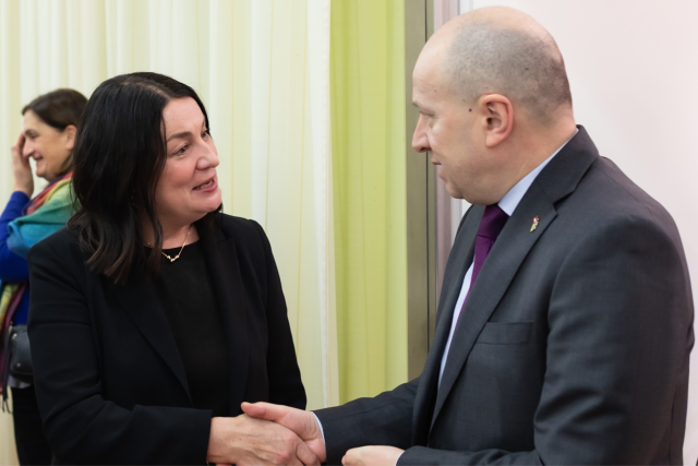 Woman (left) shakes the hand of a man (right) with a friendly look on her face. 