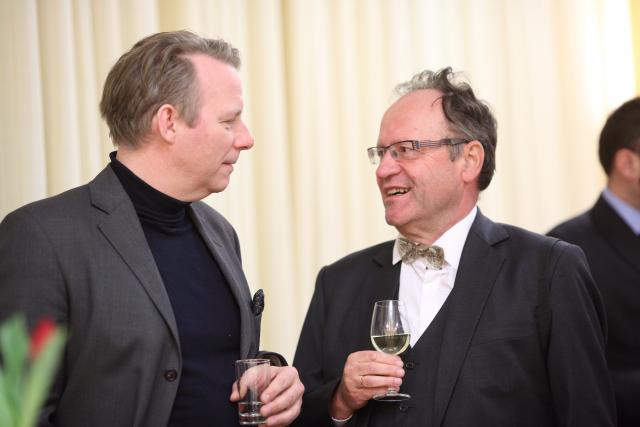 a man wearing a suit and tie holding a wine glass