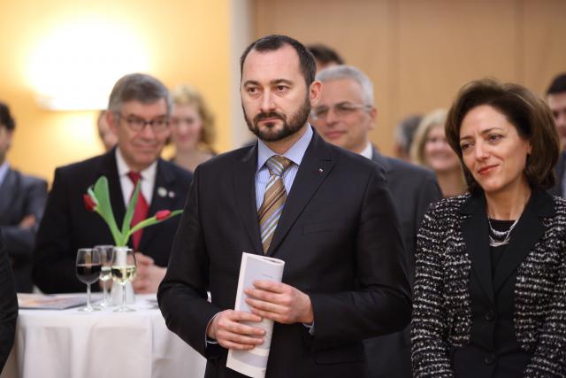 a group of people standing next to a person in a suit and tie