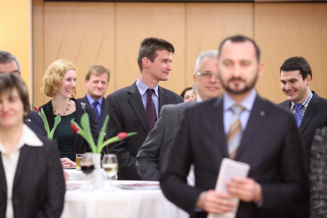 a group of people standing next to a person in a suit and tie