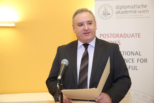 a man wearing a suit and tie smiling at the camera