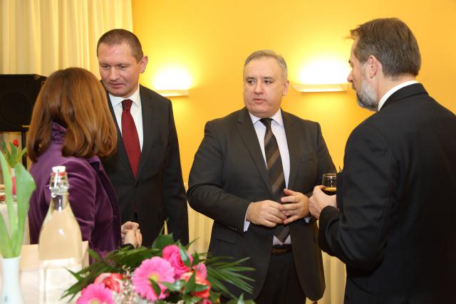 a group of people standing next to a person in a suit and tie