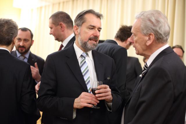 a group of people standing next to a man in a suit and tie