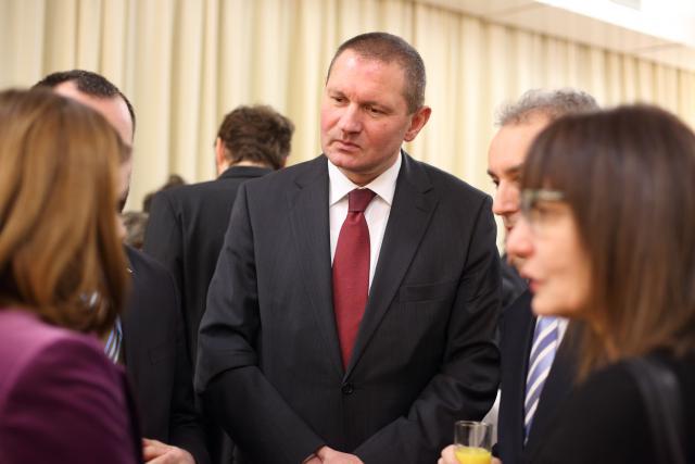 a group of people standing next to a person in a suit and tie