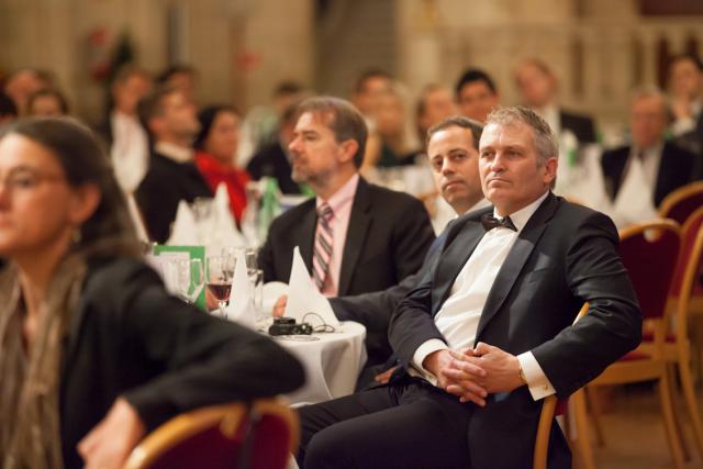 a group of people sitting next to a person in a suit and tie