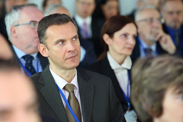 a man wearing a suit and tie standing in front of a crowd