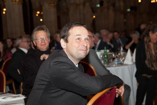 a man sitting at a table in front of a crowd