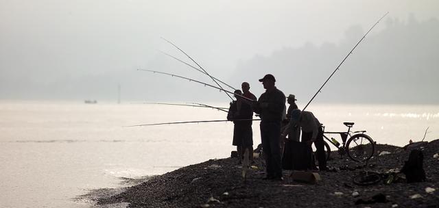 fishermen standing next to a body of water