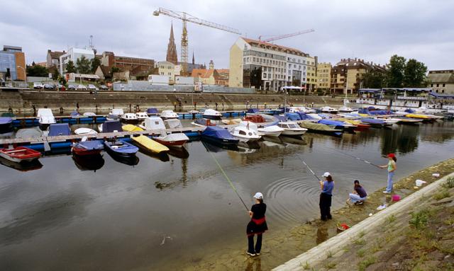 a group of people angling and boats on a body of water