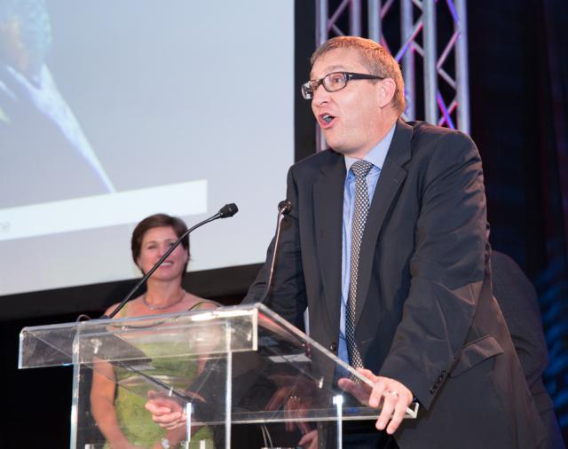 a man in a suit standing in front of a stage