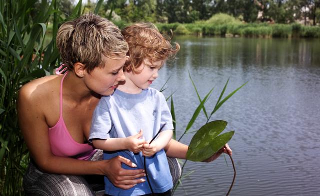 a little boy and a woman sitting next to the water