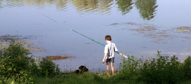 a boy standing next to a body of water