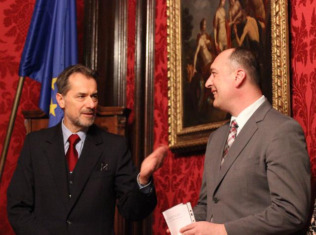 a person wearing a suit and tie standing in front of a curtain