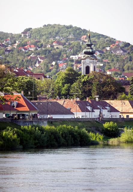 a church with a city in the background and a body of water in the foreground