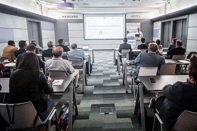 Group of people sitting in a room in front of a large presenting screen 