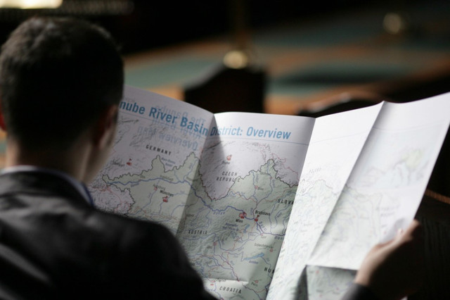 A man from the back reading from a map open in fron of him 