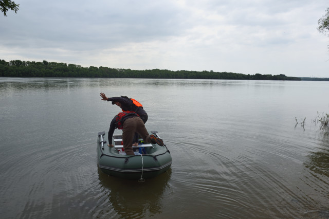 two men in a boat sampling water 