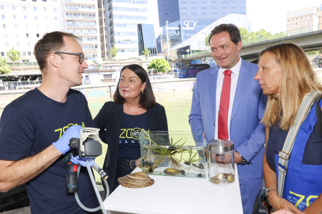 A group of 4 people standing by an aquarium and listening to an expert 