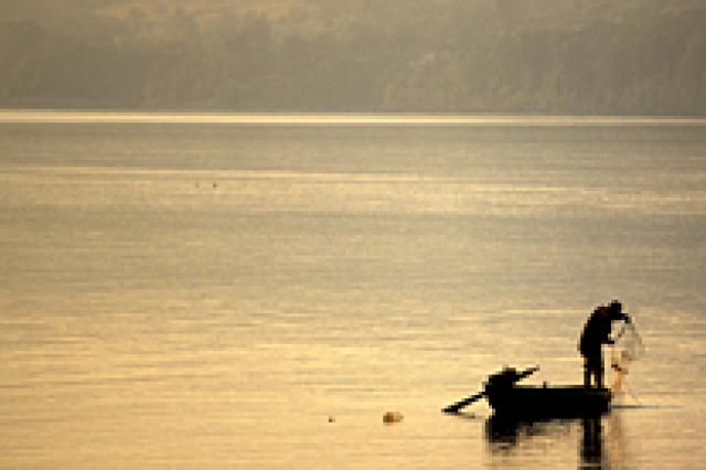 a fisherman standing on a boat on a body of water