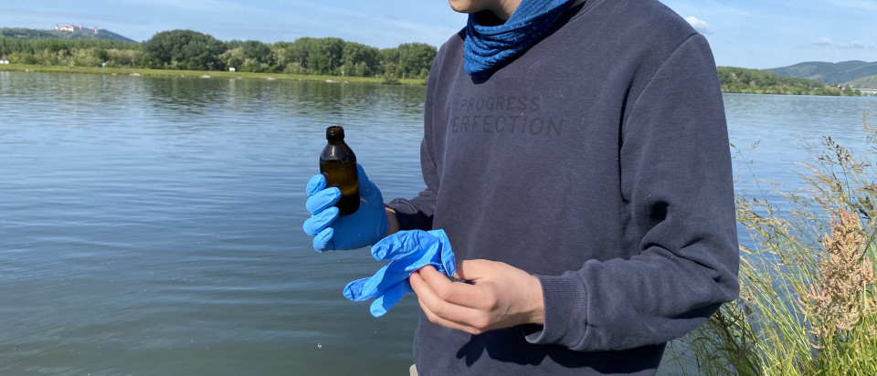 a man stands at the river with a vial in his hand 