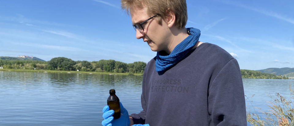 a man stands at the river with a vial in his hand 