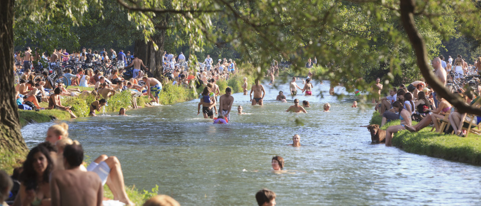 crowds of people on the banks of a river, some in the water  