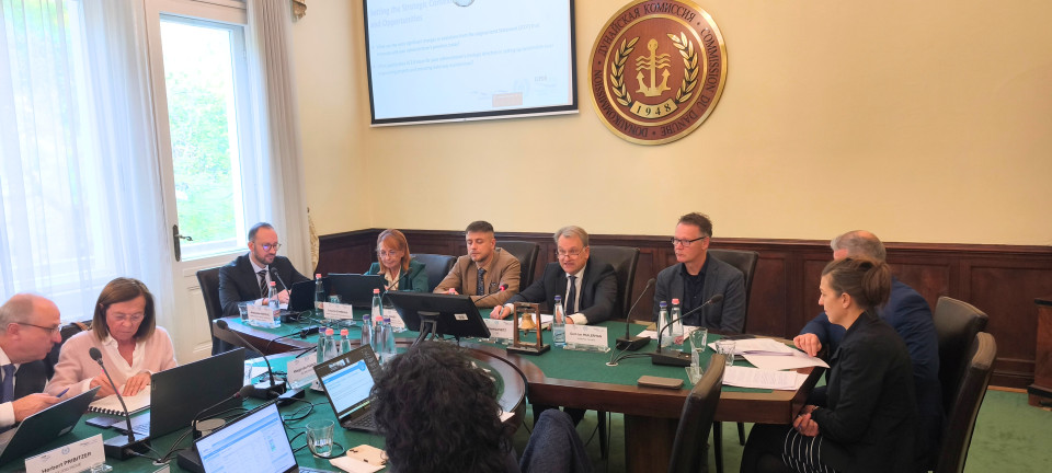 Several people sit gathered around a meeting table. 